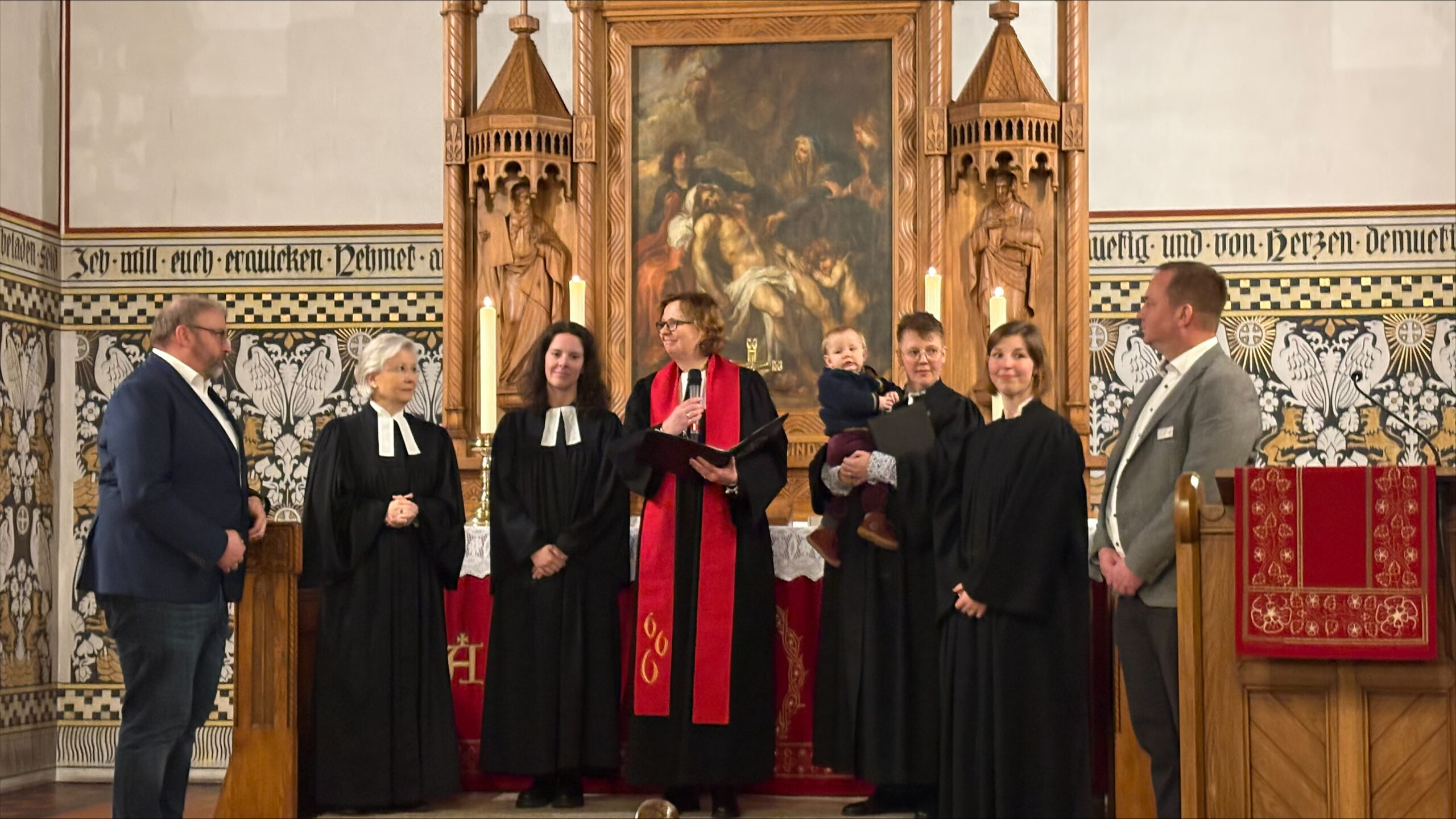 Die neue Pastorin steht in einer Gruppe Menschen vorm Altar der Kirche
